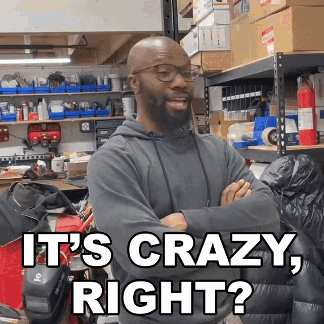 a man stands in a garage with his arms crossed and says " it 's crazy right "