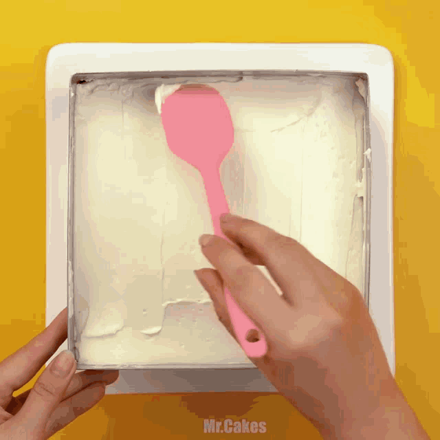 a person is holding a pink spoon over a cake that says mr.cakes on it