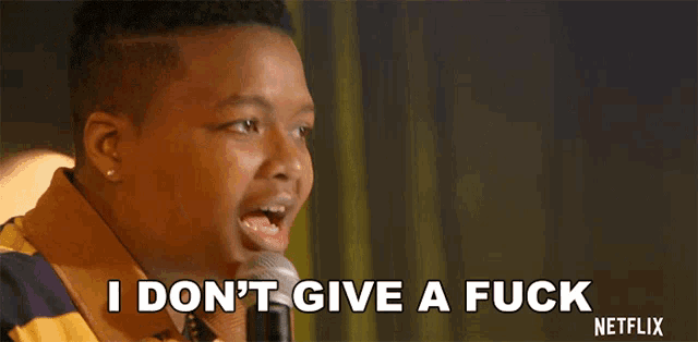 a man speaking into a microphone with the words " i don 't give a fuck " on the bottom
