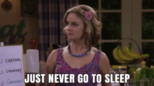 a woman with a flower in her hair is standing in front of a sign that says just never go to sleep