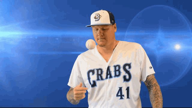 a man wearing a crabs jersey throws a baseball