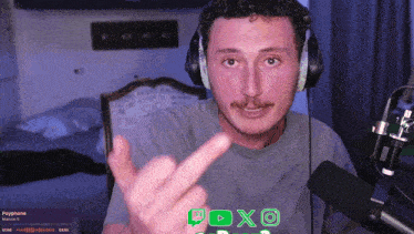 a man wearing headphones is giving the middle finger in front of a microphone