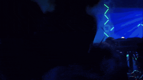 a man and a woman are dancing in a dark room with blue lights