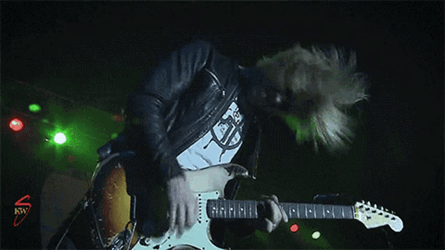 a man is playing a guitar in front of a sign that says rnv