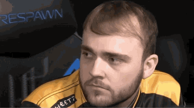 a man with a beard is wearing a yellow and black jacket with the word heet7 on it