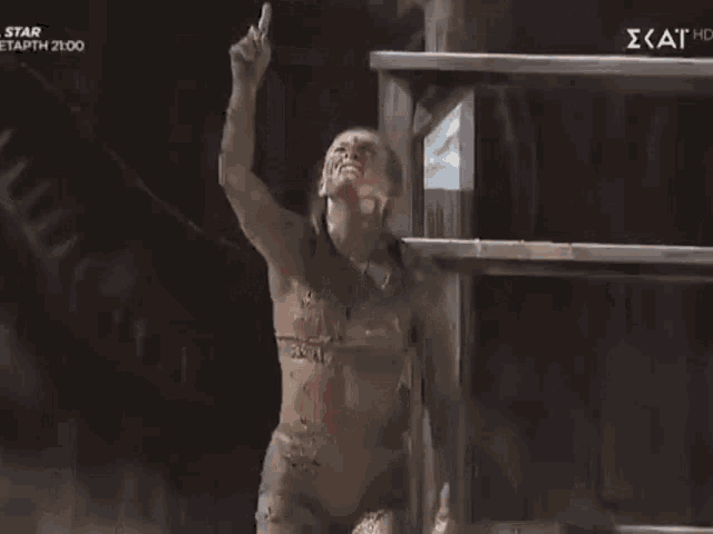 a woman covered in mud is standing in front of a sign that says star on it