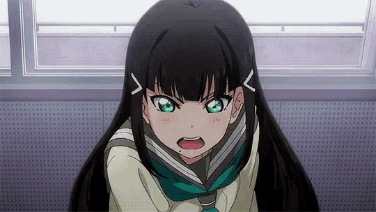 a girl with long black hair and green eyes is sitting in front of a window with her mouth open .