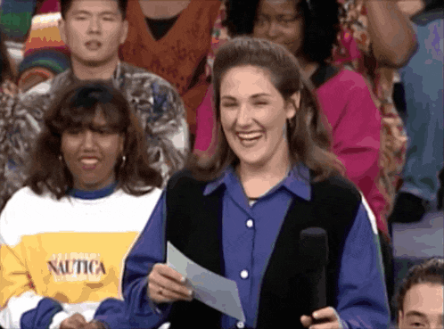 a woman wearing a nautica sweater is smiling while holding a piece of paper