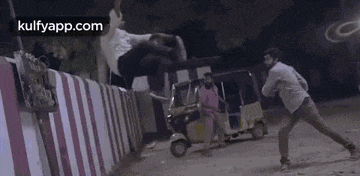 a man is playing a game of cricket in front of a rickshaw at night .