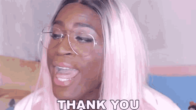 a woman with pink hair and glasses is giving a thank you sign .