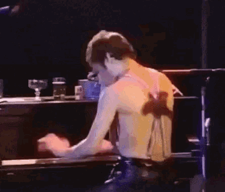 a man is playing a piano without a shirt on