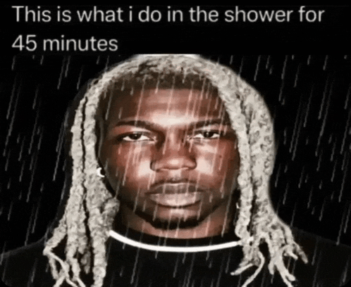 a man with dreadlocks is taking a shower with rain falling on his head .