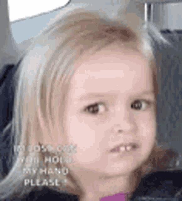 a little girl is sitting in the back seat of a car making a funny face .