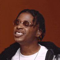 a man wearing sunglasses is covering his face with his hands