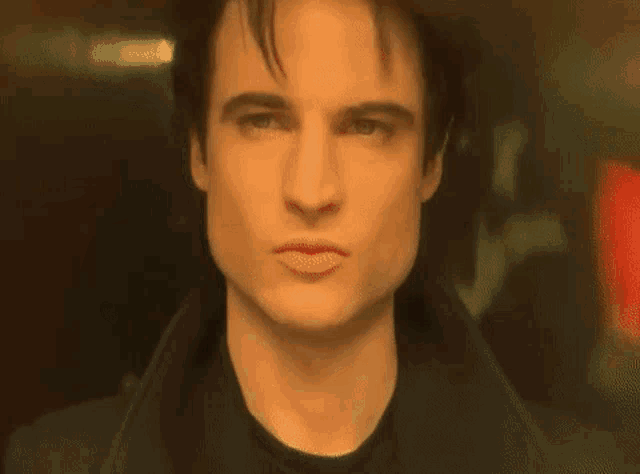 a close up of a man 's face with a black shirt on looking at the camera .