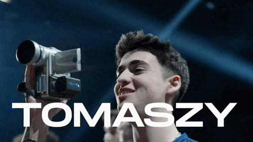 a young man is holding a video camera with the name tomasz on it