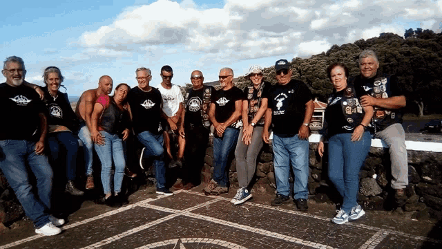 a group of people posing for a picture with one man wearing a t-shirt that says ' biker '