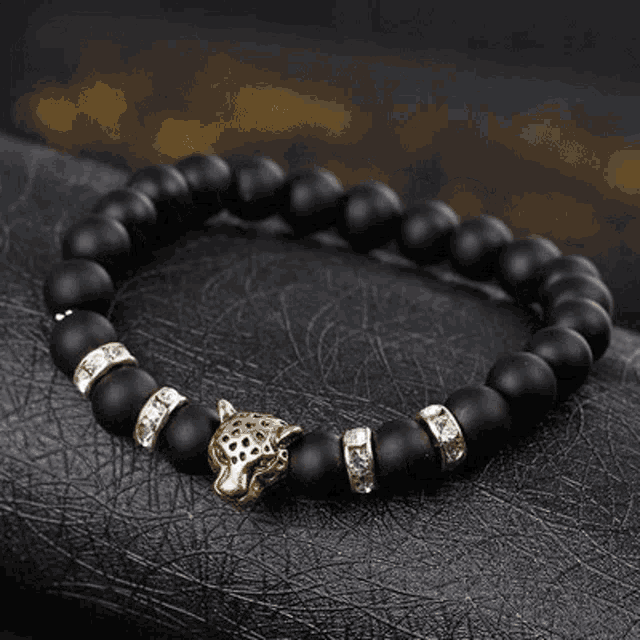 a bracelet with black beads and a gold leopard head on it .