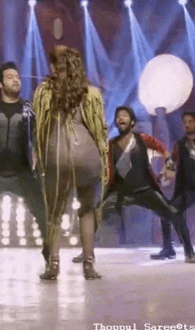 a woman is dancing on a stage with a group of people .