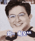 a man with glasses is smiling and making a heart with his hands .