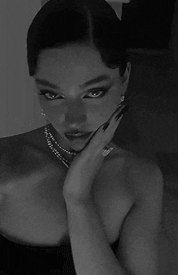 a woman is wearing a pearl necklace and earrings in a black and white photo .
