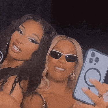 two women wearing sunglasses are taking a selfie with their phones .