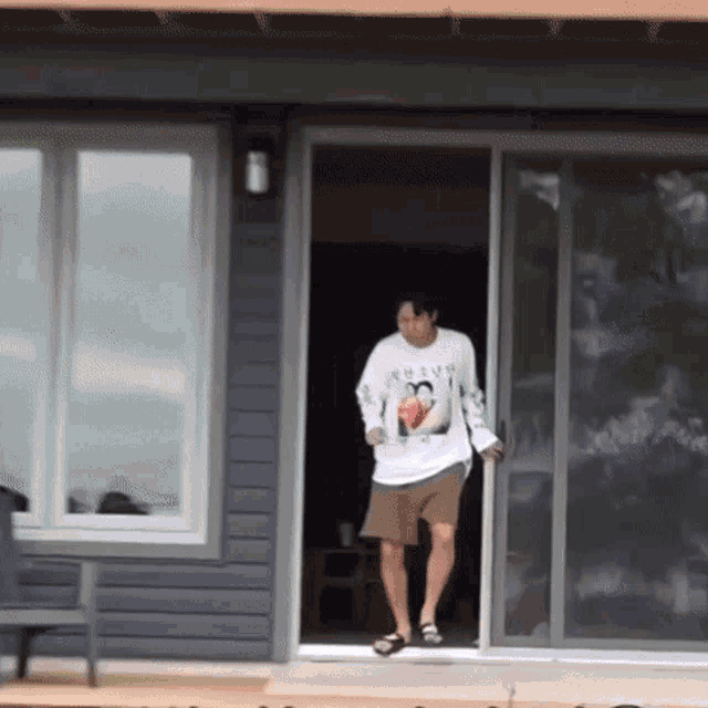 a man wearing a shirt that says ' always ' on it is walking out of a house