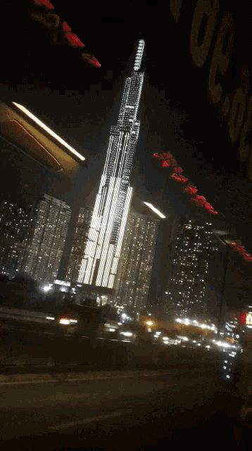 a very tall building is lit up at night in front of a sign that says ' vegas ' on it