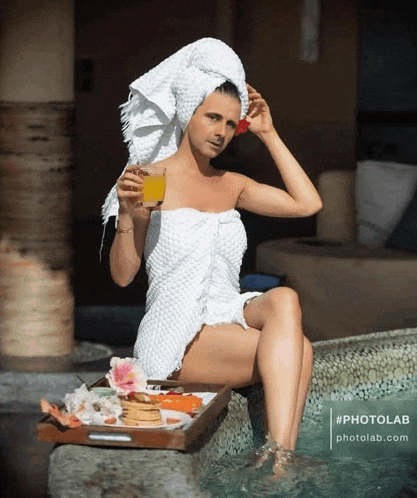 a woman with a towel wrapped around her head is sitting in a pool holding a drink