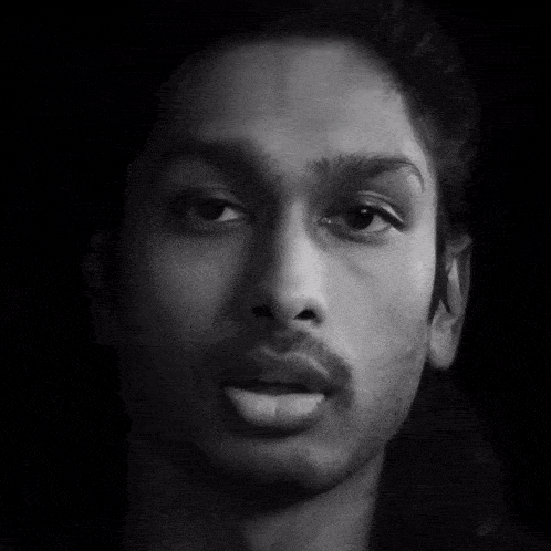a black and white photo of a man 's face with a hand pointing at it