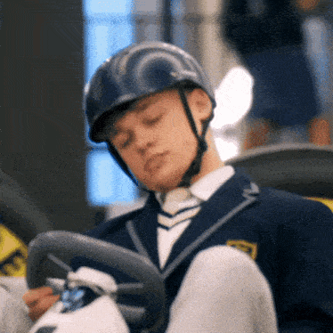 a man wearing a helmet is sitting in a go kart with his eyes closed