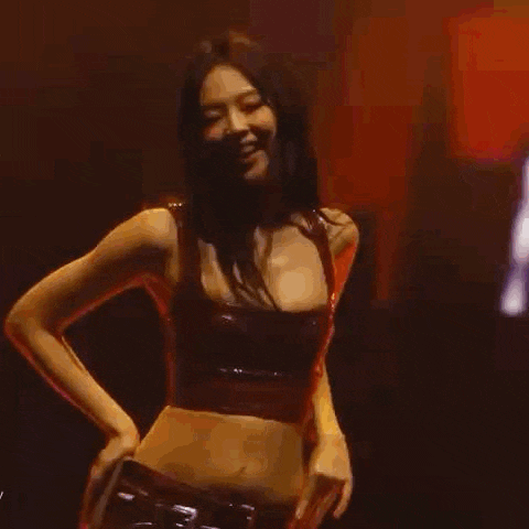 a woman is dancing in a dark room with her eyes closed and her tongue out .