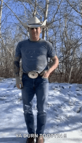 a man in a cowboy hat is standing in the snow .