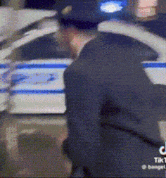 a police officer is standing next to a police car .