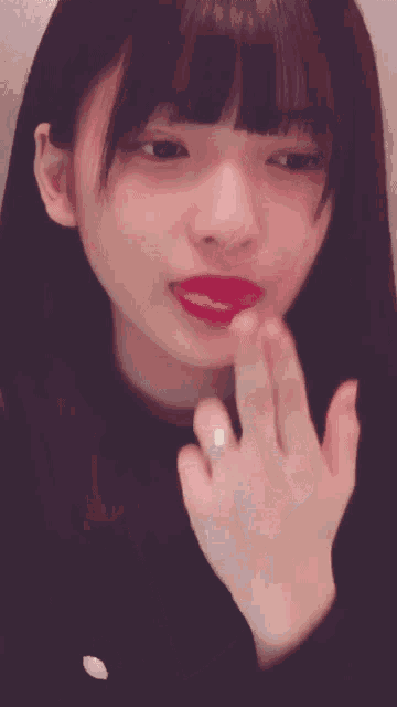 a close up of a woman 's face with her eyes closed and a ring on her finger