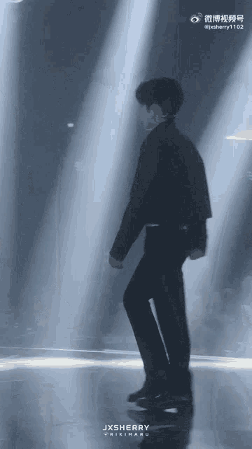 a man in a black jacket is dancing on a stage with jxsherry written on the bottom right