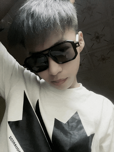 a boy wearing sunglasses and a white shirt with a black maple on it
