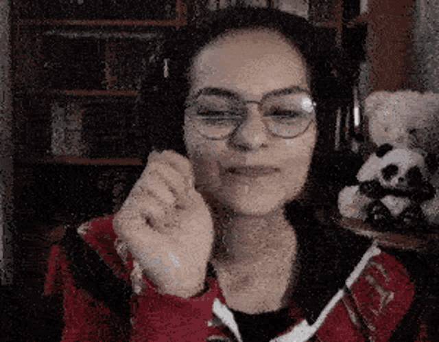 a woman wearing glasses and headphones with a panda bear behind her