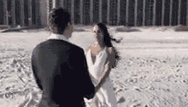 a bride and groom are dancing on a beach .