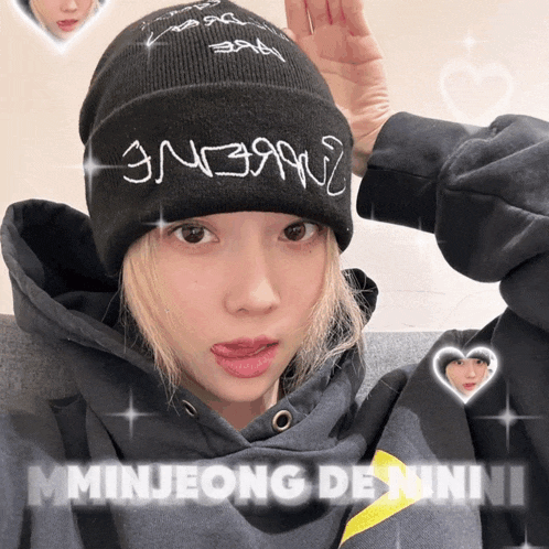 a girl wearing a black beanie and a grey hoodie with the name minjeong denni on the bottom