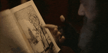 a man with a beard is pointing at a page in a book that says ' no. 2 ' on it