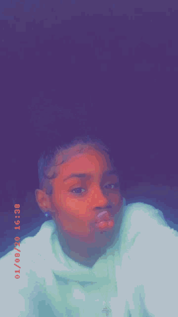 a woman is making a funny face with her mouth open and a purple background .