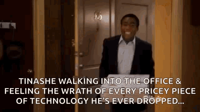 a man in a suit is walking into a doorway holding a box of pizza .