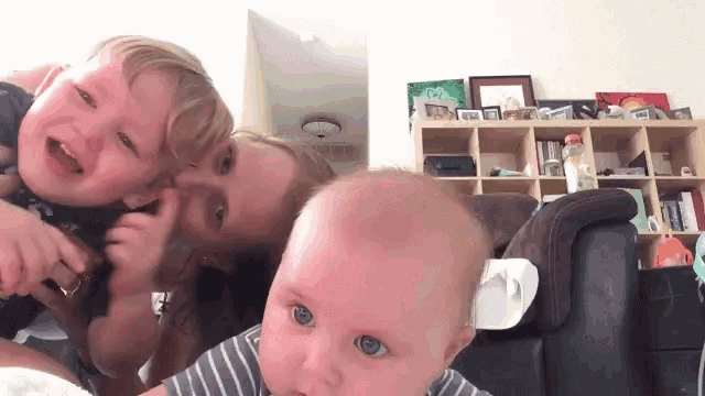 a woman is kissing a baby while holding two other children