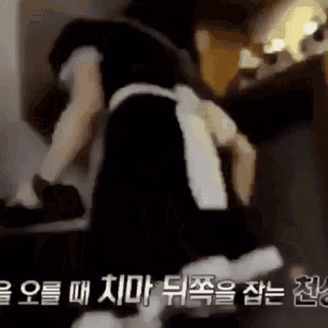 a man in a maid costume is standing in a room with chinese writing on the bottom .