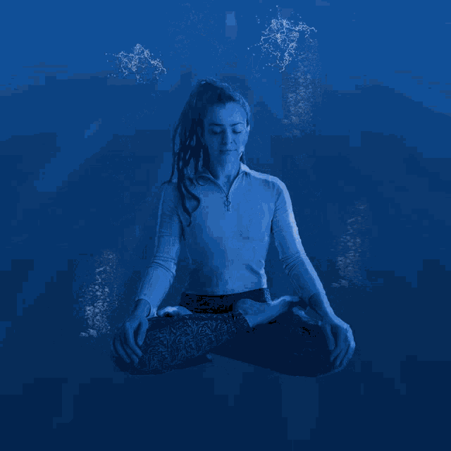 a woman sitting in a lotus position with water coming out of her face