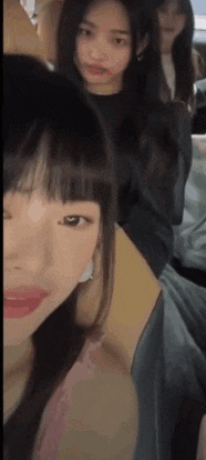 a group of young women are sitting next to each other in a room and looking at the camera .