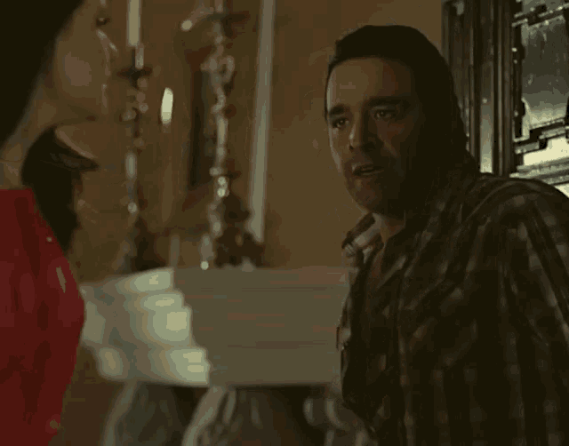 a man in a plaid shirt talks to a woman in a red dress