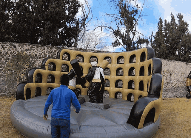 a man in a blue shirt is standing in front of a giant inflatable wrestling ring