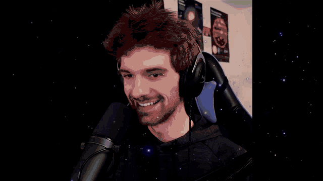 a man wearing headphones is smiling in front of a microphone with stars in the background
